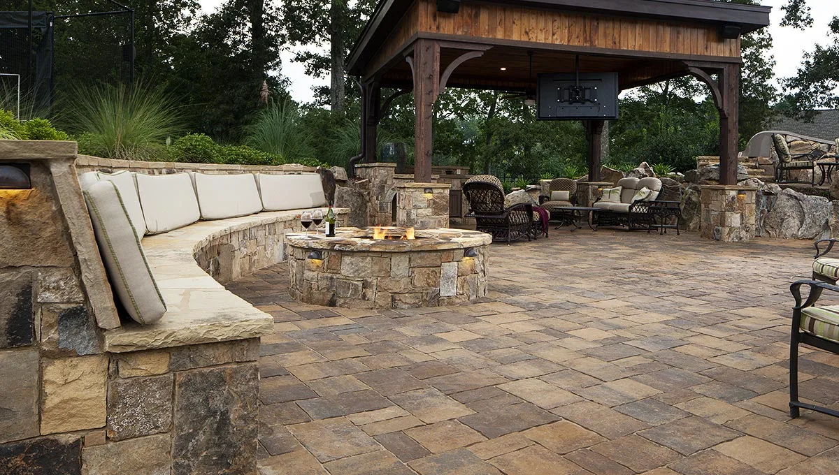 Large stone paver patio with fire pit and seating wall.